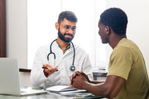 Indian doctor therapist in white coat consulting supporting patient in modern clinic hospital